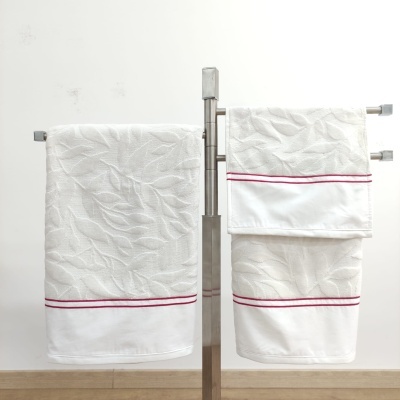 Conjunto de toalhas brancas texturizadas com risca vermelha penduradas no suporte metálico