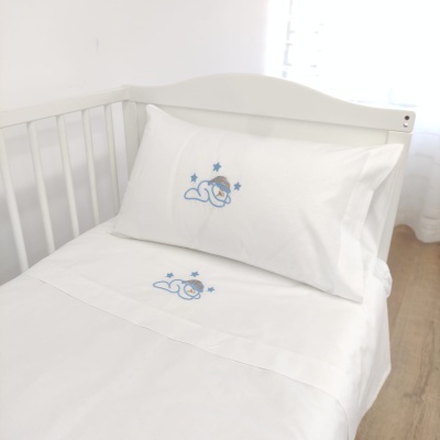 Lençol e fronha de berço brancos com bordado de bebé e estrelas