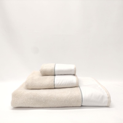 Conjunto de três toalhas bege com bordas brancas empilhadas