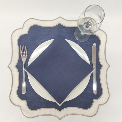 Conjunto de mesa com placemat creme e dourado, prato branco, guardanapo azul, talheres aço inox e copo de vinho