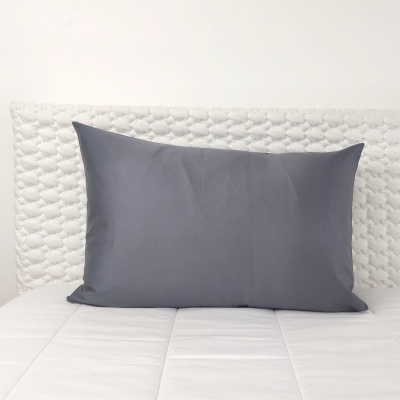 Almofada cinzenta retangular no colchão branco com cabeceira texturada