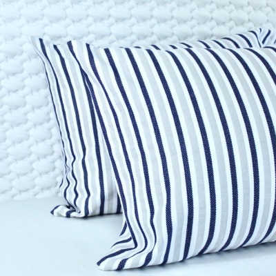 Duas almofadas com riscas azuis e brancas em fundo branco texturizado