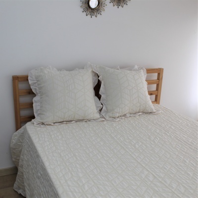 Cama de madeira clara com edredão e almofadas bege com padrão geométrico