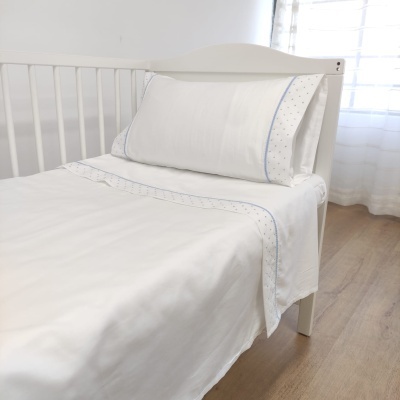 Cama de criança com roupa de cama branca decorada com estrelas azuis