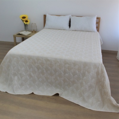 Cama casal com edredão branco floral e almofadas brancas, cabeça de madeira, mesa com girassóis