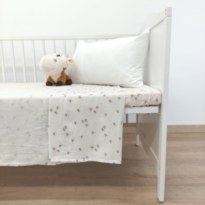 Cama de criança branca com roupa de cama bege estampada e peluche de vaca