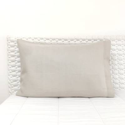 Almofada cinza claro sobre cabeceira branca texturizada e superfície branca