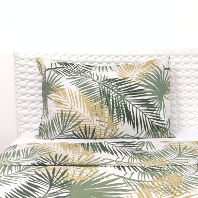 Roupa de cama com padrão de folhas tropicais verdes e amarelas sobre fundo branco