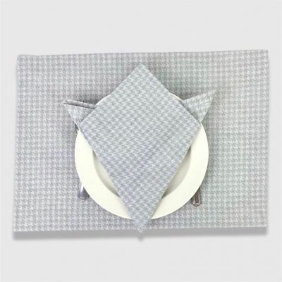 Jogo americano e guardanapo cinza e branco com padrão pied-de-poule sobre prato branco