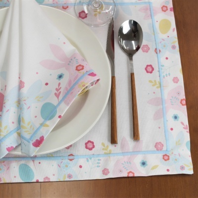 Jogo americano e guardanapo florais com prato branco e talheres de madeira sobre mesa de madeira