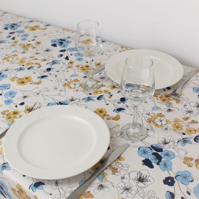 Mesa com toalha floral, pratos brancos, facas e copos de vidro