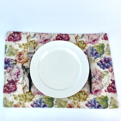Lugar americano com padrão de uvas e flores e prato branco com talheres