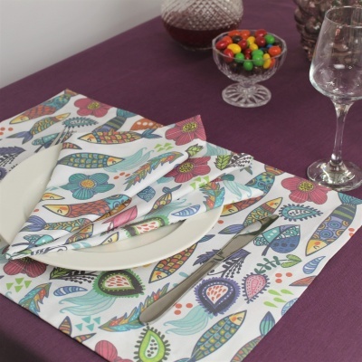 Jogo americano e guardanapo coloridos com padrão floral e talheres em mesa com toalha roxa