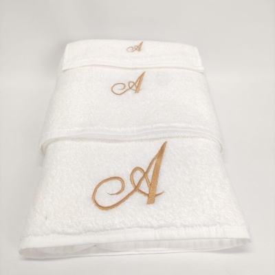 Conjunto de três toalhas brancas com bordado dourado da letra A.