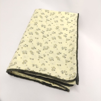 Toalha ou manta amarela com pequenas flores cinza e amarelas e bordas cinza escuro