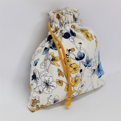 Saco de tecido branco com flores azuis e amarelas e cordão amarelo