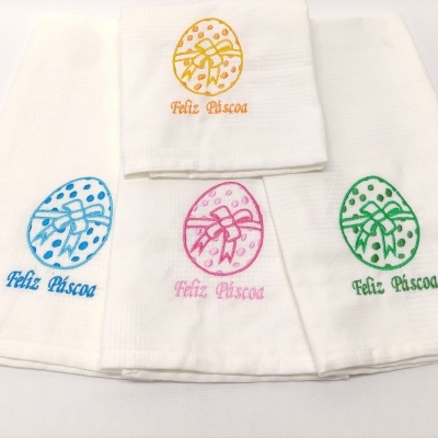 Guardanapos brancos com bordados coloridos de ovos de Páscoa e texto 'Feliz Páscoa'