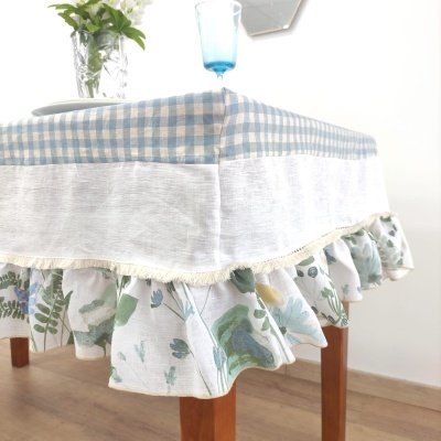 Toalha de mesa padrão xadrez azul e branco com folho floral em mesa de madeira