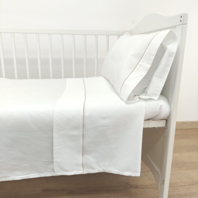 Berço branco com roupa de cama branca e detalhes bege