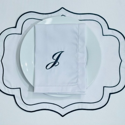 Jogo americano e guardanapo branco com detalhes pretos sobre prato branco