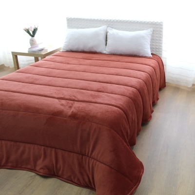 Cama com colcha castanha e almofadas brancas num quarto iluminado