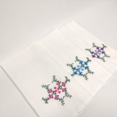 Três panos de cozinha brancos com bordados florais coloridos