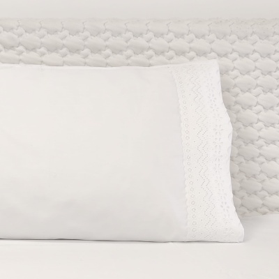 Fronha branca com bordado em renda sobre almofada cinza claro texturada