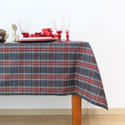 Mesa com toalha xadrez em tons cinza e vermelho e decoração com velas vermelhas.
