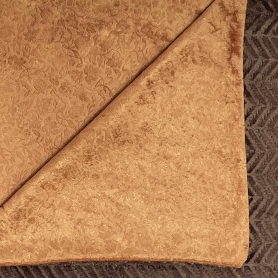 Manta castanha com padrão floral sobre superfície cinzento escuro com padrão zig-zag