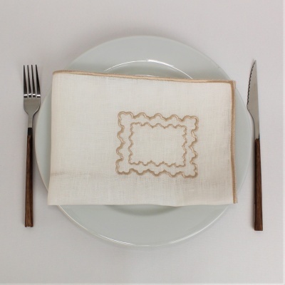 Guardanapo branco bordado em prato branco com talheres ao lado