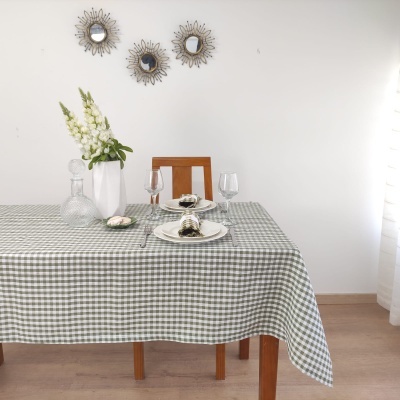 Mesa com toalha xadrez verde e branca, arranjo de flores, utensílios de mesa e espelhos decorativos na parede
