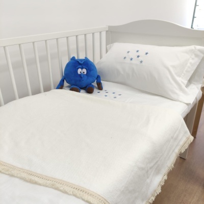 Berço branco com roupa de cama creme e peluche azul sentado
