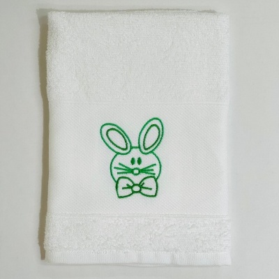 Toalha branca com bordado de coelho verde sobre fundo branco