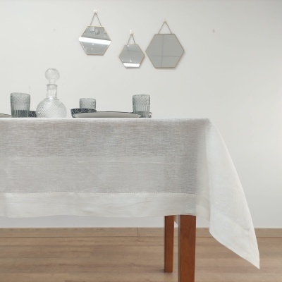 Mesa com toalha branca e acessórios de vidro em fundo com espelhos geométricos pendurados