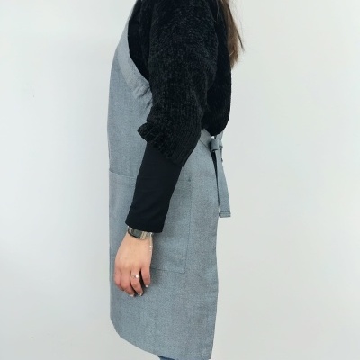 Pessoa a usar avental cinza claro com bolso, fundo branco