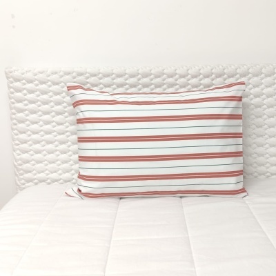 Travesseiro com fronhas às riscas sobre cama branca acolchoada