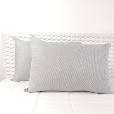 Duas almofadas cinzentas numa cama branca com cabeceira acolchoada