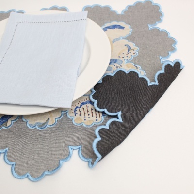 guardanapo azul claro sobre prato branco em centro de mesa floral azul, bege e preto