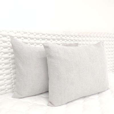 Duas almofadas brancas com padrão bordado circular num fundo branco acolchoado