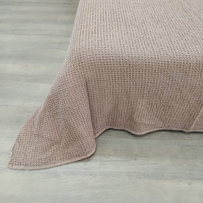 Manta rosa claro com padrão waffle sobre chão de madeira