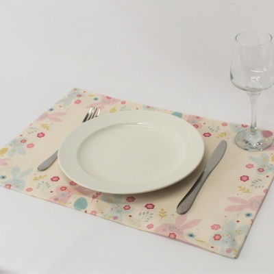 Jogo americano floral com prato branco, talheres metálicos e taça de vidro