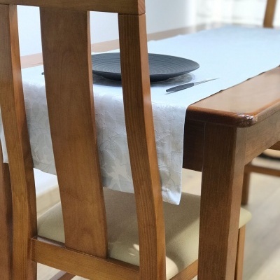 Conjunto de mesa de jantar em madeira castanha com toalha branca e prato preto