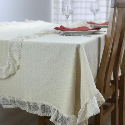 Toalha de mesa branca com renda numa mesa de madeira com pratos, guardanapos vermelhos e taças de vidro