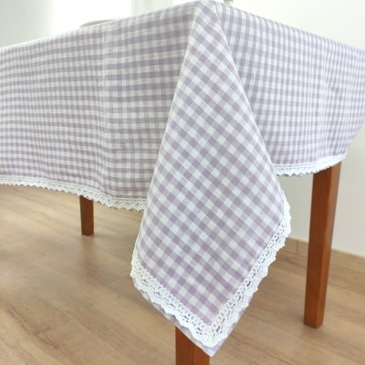 Toalha de mesa xadrez lilás e branco com renda branca numa mesa de madeira