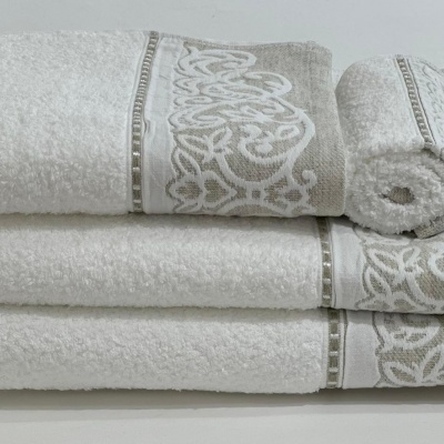 Conjunto de toalhas de banho branco e bege com bordado decorativo.