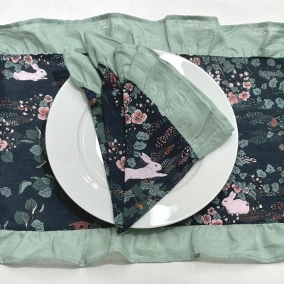 Jogo americano e guardanapo com padrão de coelhos e folhas sobre prato branco