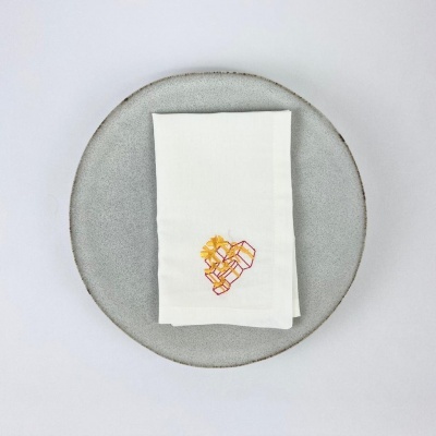 Toalha branca com bordado de caixas coloridas em prato cinza