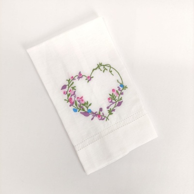 Guardanapo branco com bordado colorido em forma de coração de flores e folhas