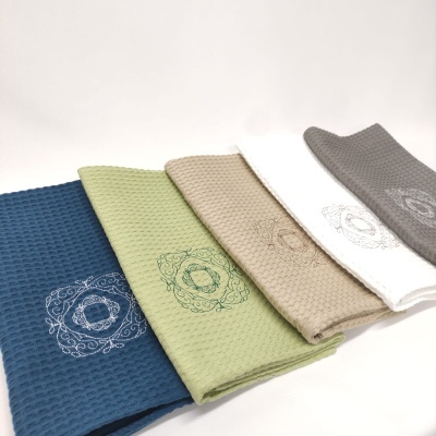 Cinco panos de cozinha coloridos com padrão de colmeia e bordados decorativos.