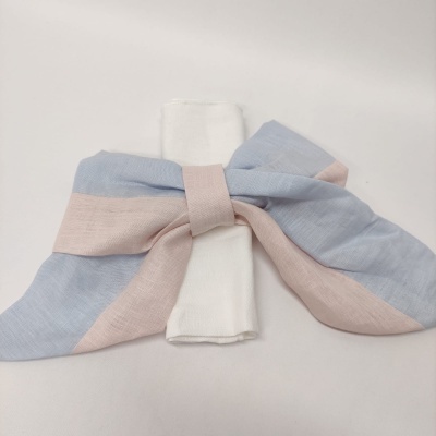 Guardanapo branco com anel de tecido em forma de laço azul claro e rosa claro